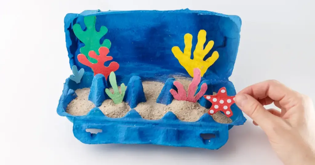 Bemalter blauer Eierkarton als Mini-Unterwasserwelt mit Sand, Korallen und Seestern – DIY-Idee für Kinde