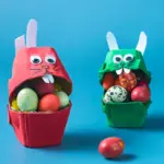 Zwei bunte Osterhasen aus bemalten Eierkartons, gefüllt mit bunten Eiern – kreative DIY-Idee zum Basteln mit Kindern an Ostern