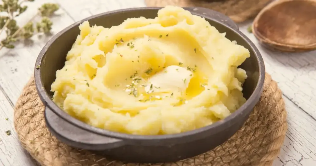 Kartoffelpüree in einer rustikalen gusseisernen Pfanne mit Butter und Kräutern.