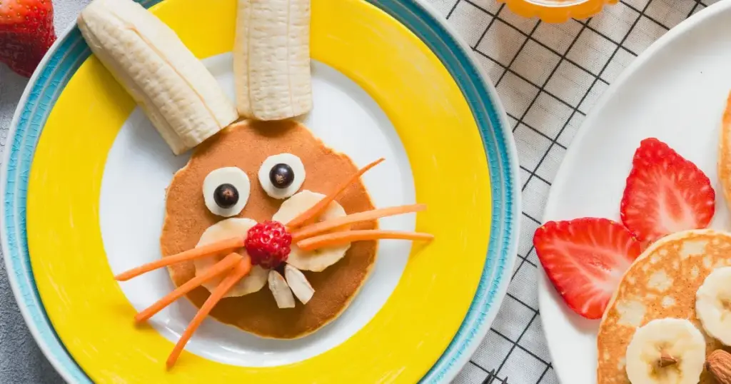 Pfannkuchen in Form eines Osterhasen, dekoriert mit Obst, serviert zum Osterfrühstück für Kinder.