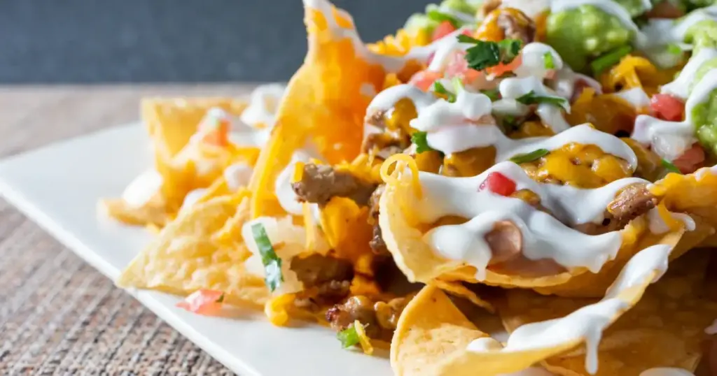 Leckere Sour Cream mit frischen Kräutern als perfekter Dip für Nachos, Kartoffeln und Gemüse.