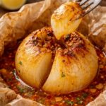 Onion Boil ohne Alufolie: Ganze, butterweich gebackene Zwiebel in Backpapier mit würziger Butter-Paprika-Sauce. Die einzelnen Zwiebelschichten werden abgezogen und als herzhafter Snack gegessen.