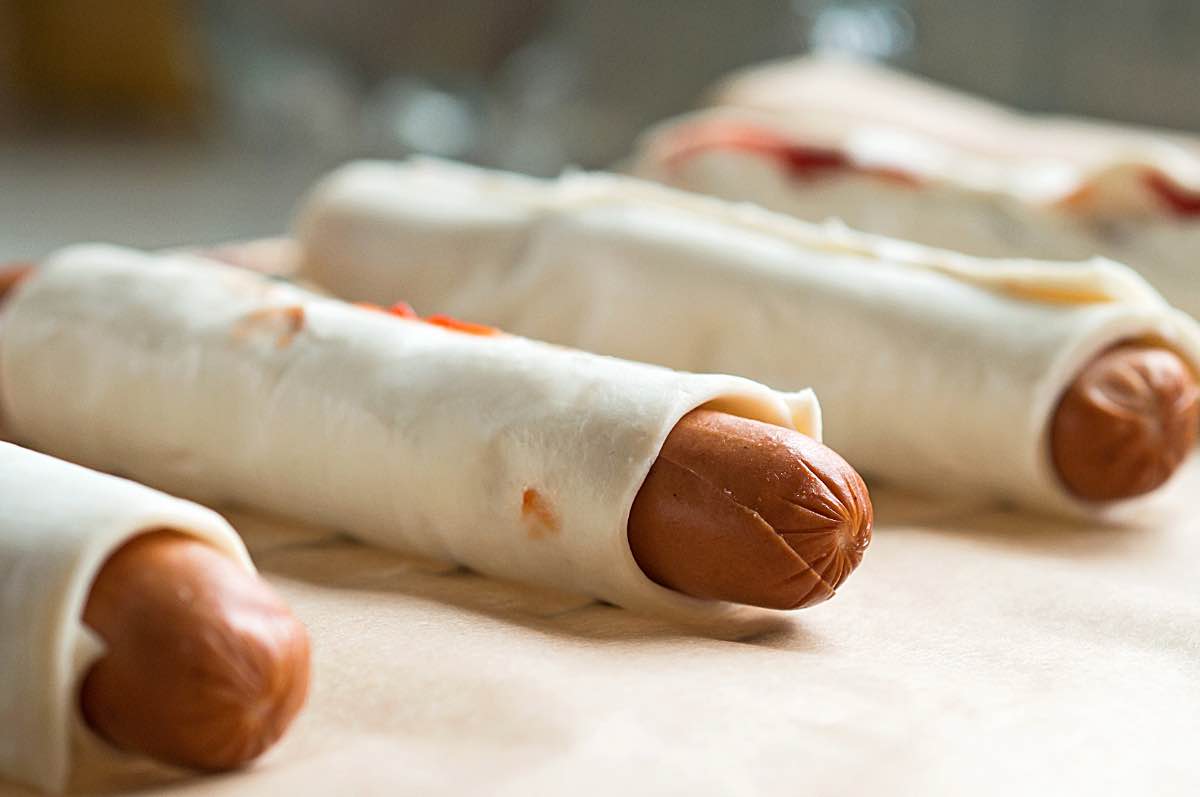 Würstchen werden in Pizzateig gerollt