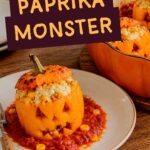 Orangefarbene Halloween-Paprika mit geschnitzten Kürbisgesichtern, gefüllt mit Reis, Mais und Feta, mit Käse überbacken und in Tomatensoße serviert.